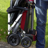 A man holding a folded up red Manual Fold+ Scooter outside