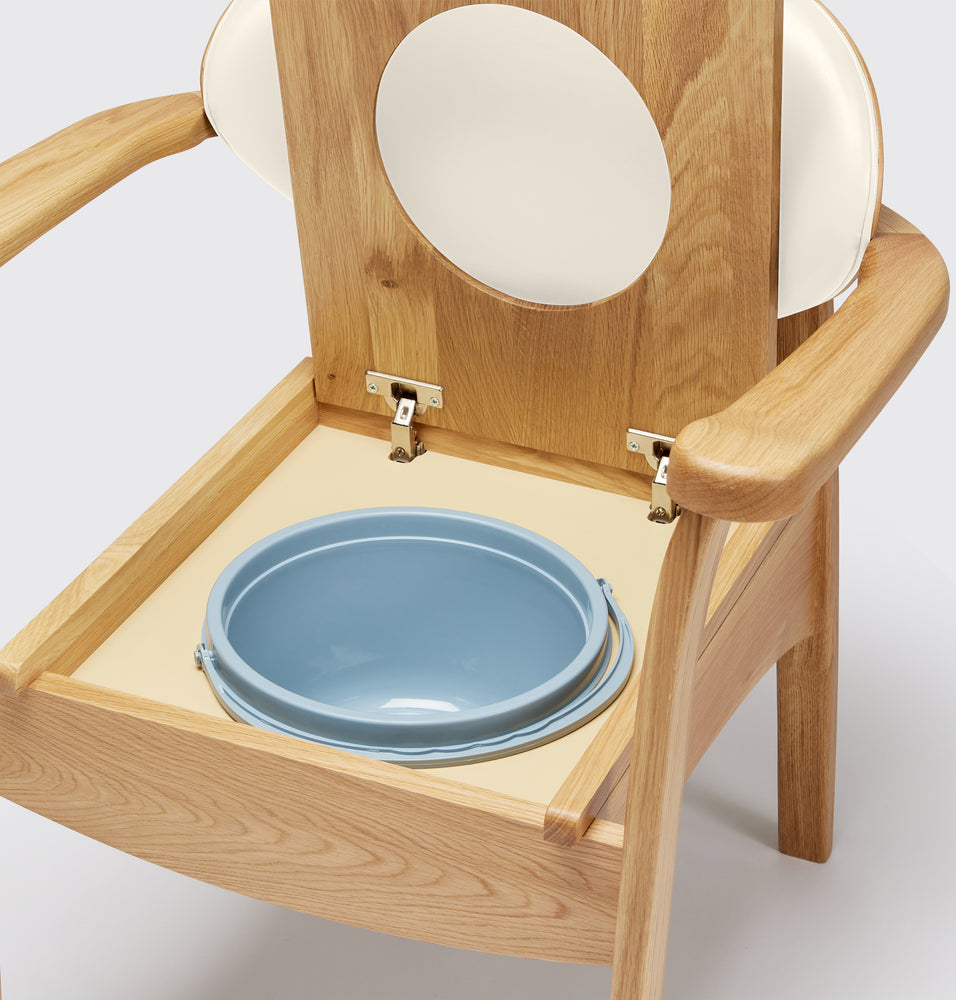 the image shows a close up of the pan on the oat coloured oak commode chair