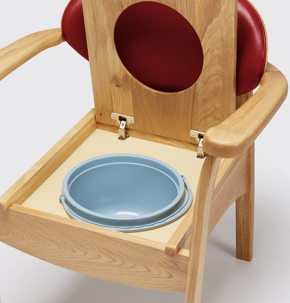 the image shows a close up of the pan on the red oak commode chair