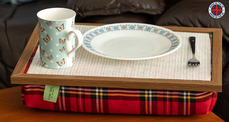 The Royal Stewart Red Tartan Lap Tray with Bean Bag on a table with a mug, plate and fork on it