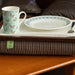 The luxury Dogtooth Lap Tray with bean bag on a table in a living room, with non slip matting, a mug, a plate and a fork on it.