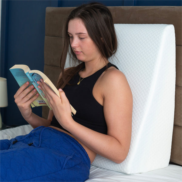 a woman sitting up in bed with the bed wedge pillow