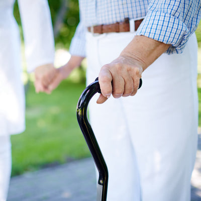 An elderly man's hand holding the top of a walking stick.