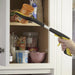 the handi grip mini reacher being used to pick up a jar of gravy from a kitchen cupboard
