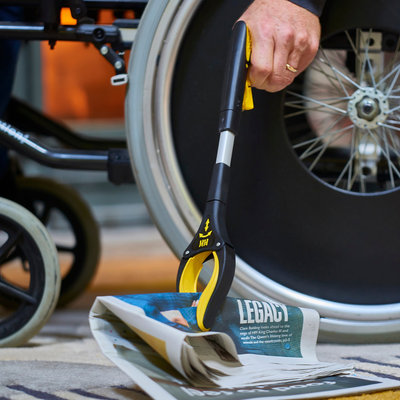 the handi grip mini reacher being used to pick up a newspaper