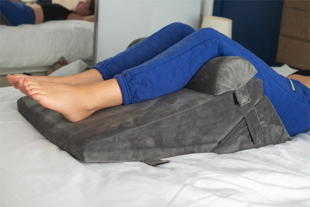 a woman using the bed wedge pillow to elevate her legs in bed