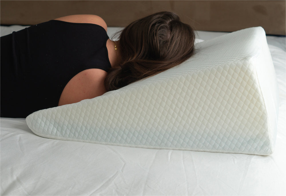 a woman using the bed wedge pillow to sleep