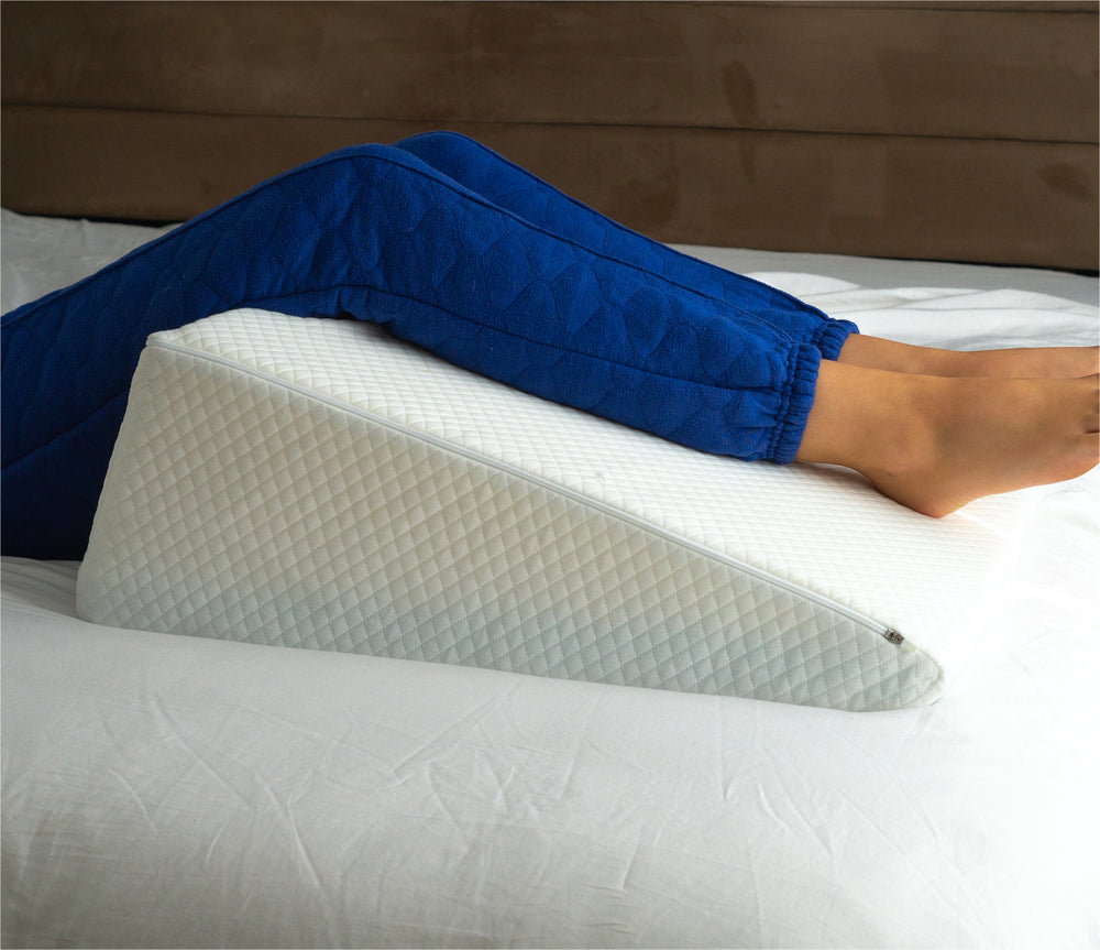 a woman using the bed wedge pillow to elevate her legs