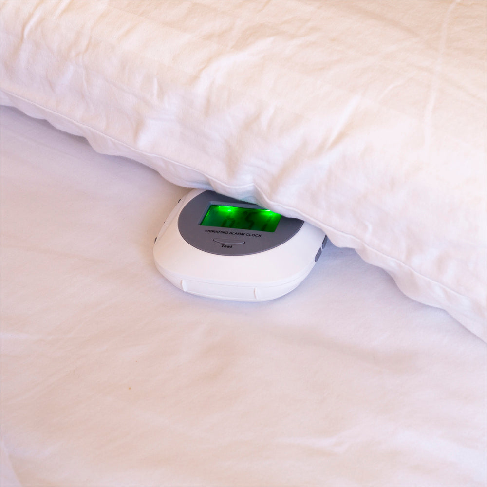 The Vibrating Alarm Clock under a pillow with its green light alarm 