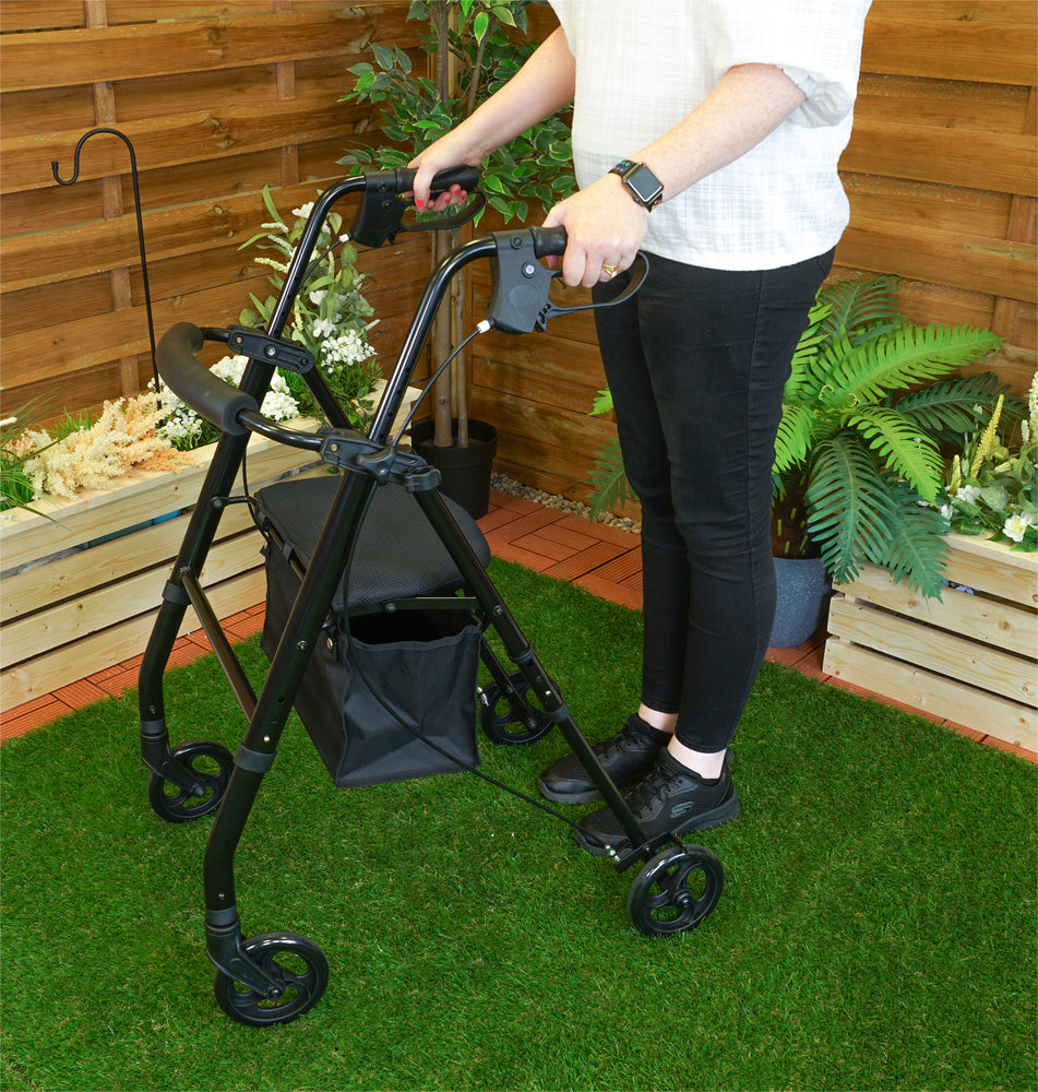 Someone using a black Lightweight Four Wheeled Rollator in a garden