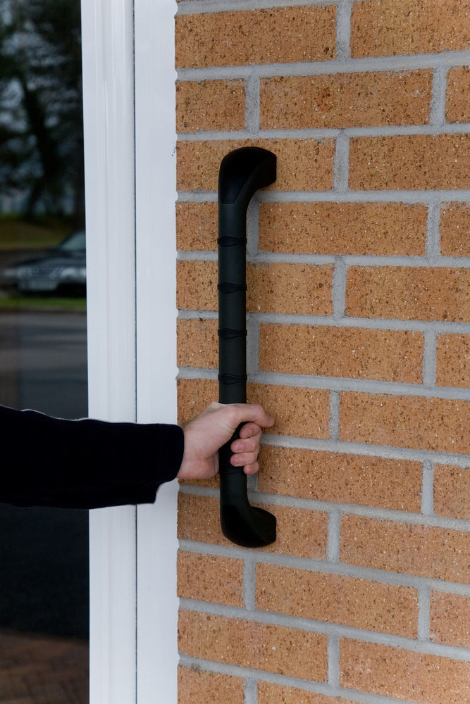 Prima outdoor grab rail fixed to an outer brick wall and a hand grasping the rail