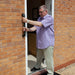Prima outdoor grab rail fitted alongside an exterior door and a man using the rail to move through the doorway