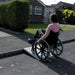 the image shows someone in a wheelchair using the axcess roll up ramp to get up a kerb