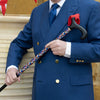 the image shows a man in a smart blue double breasted suit with gold buttons, holding the crowning glory classic cane.