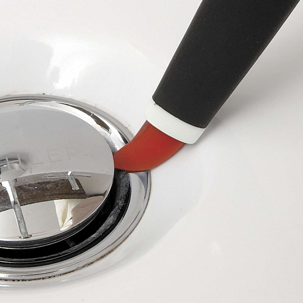 the wiper blade on the small brush being used to clean around a sink plug