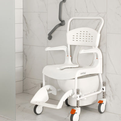 The image shows an Etac Clean Shower Commode Chair placed over a wall mounted toilet