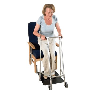 A woman using a Dycem Floor Mat to help get up from a chair to her walking frame