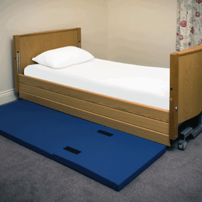 A bed with a fall mat besides it