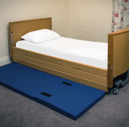 A bed with a fall mat besides it