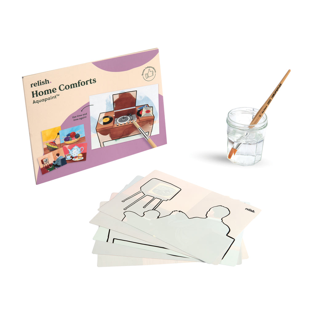shows the home comforts aqua paint box with a painting sheet and a paintbrush in a glass of water