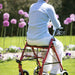 shows a woman sitting on the seat of the SR8 Steel Rollator in a garden