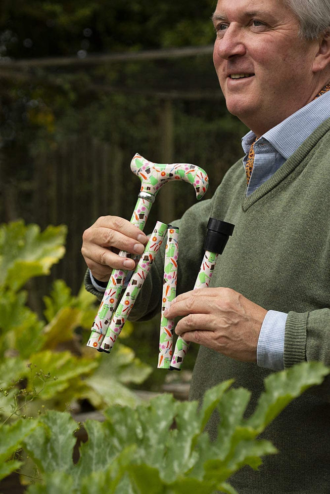 the image shows a man in the garden holding the classic canes folding fashion derby cane with a garden design