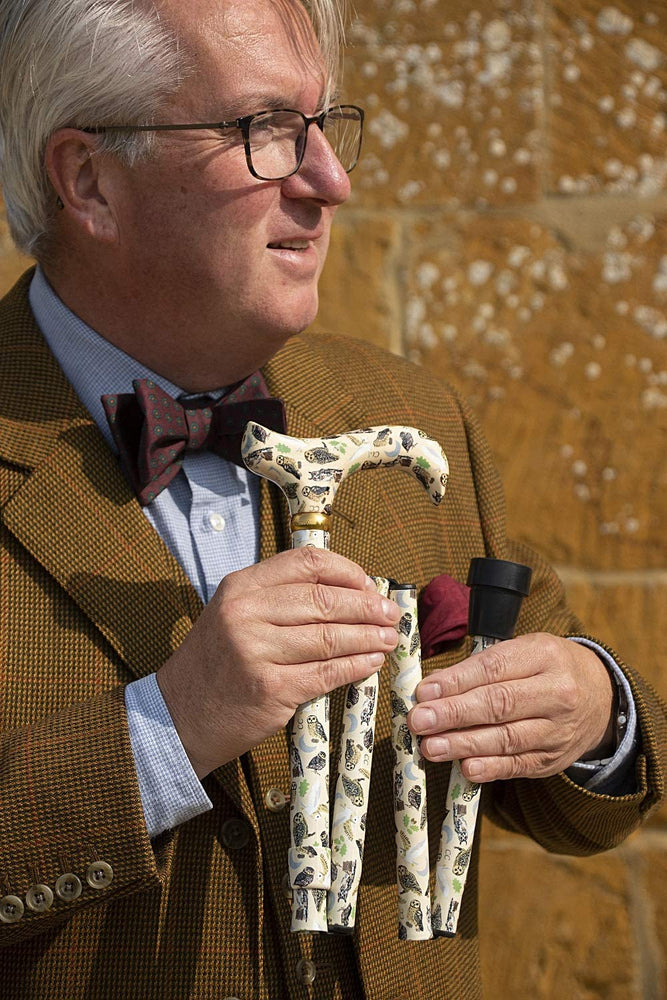 the image shows a smartly dressed man holding the classic canes folding fashion derby cane with the british owl design