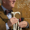 the image shows a smartly dressed man holding the classic canes folding fashion derby cane with the british owl design