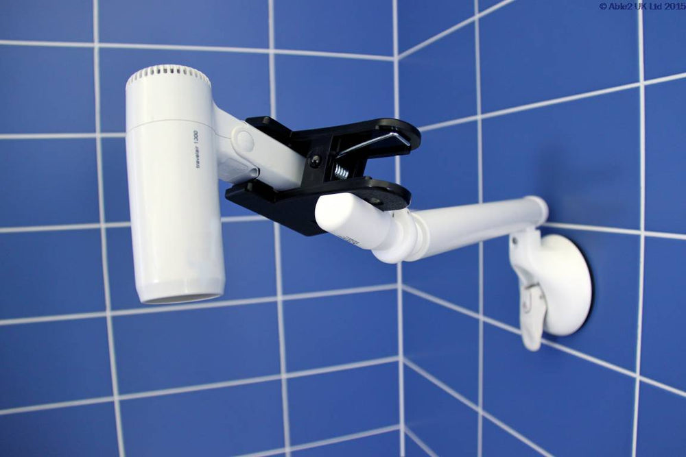 shows the Mobeli Clip Holder with swivel arm attached to a blue tiled wall and holding a portable hair dryer