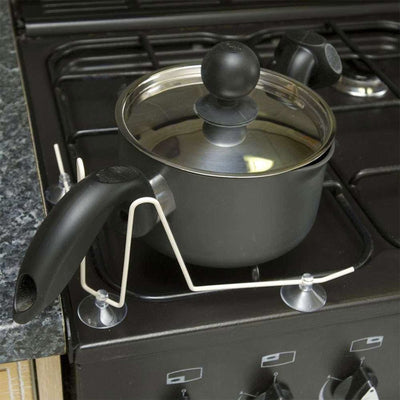 shows the pan handle holder in place on a gas hob, being used to keep a pan in one place