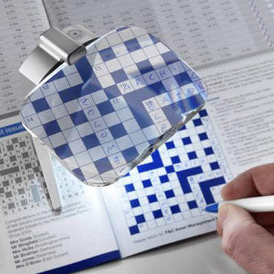 the image shows the eschenbach scribolux illuminated stand magnifier being used to complete a crossword