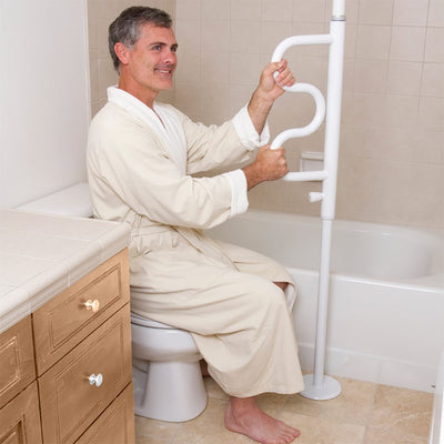 shows a man in a dressing gown, using the Security Pole with Grab Bar to rise from a low toilet seat