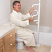 shows a man in a dressing gown, using the Security Pole with Grab Bar to rise from a low toilet seat