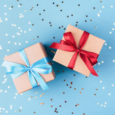 Two wrapped presents. One present has a blue ribbon, and one has a red one. The presents are 