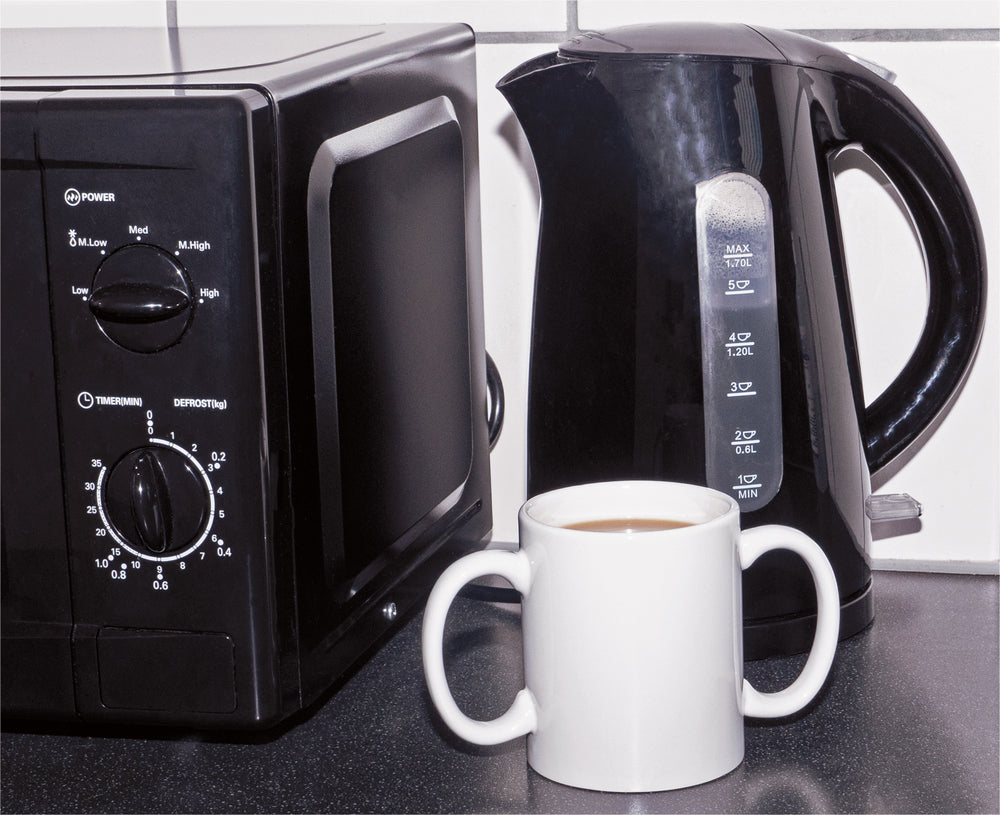 Two handled mug pictured next to a kettle and a microwave