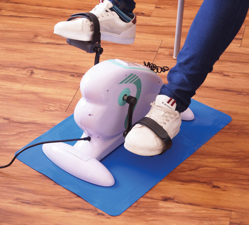 shows someone using a pedal exerciser on a large non slip silicone mat in blue