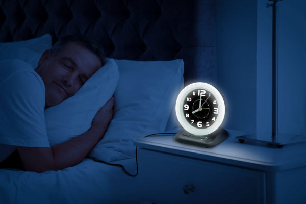Wake n shake alarm clock on bedside cabinet whilst man sleeps 