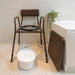 Stackable commode chair in bathroom with lid off