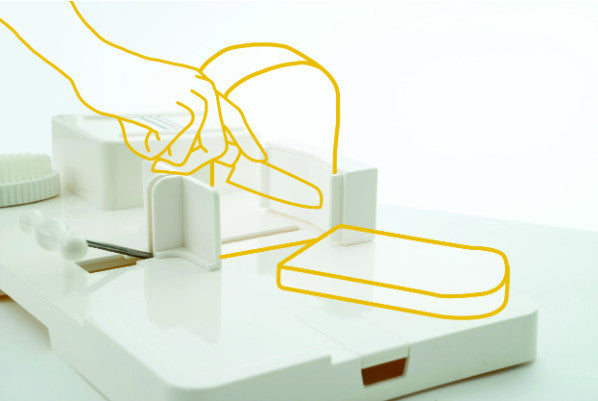 A diagram showing how the food workstation can be used to hold a loaf of bread securely, so it can be safely sliced.