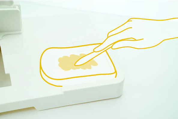 A diagram showing how the Food Workstation can be used to hold a slice of bread securely, so that it can be buttered