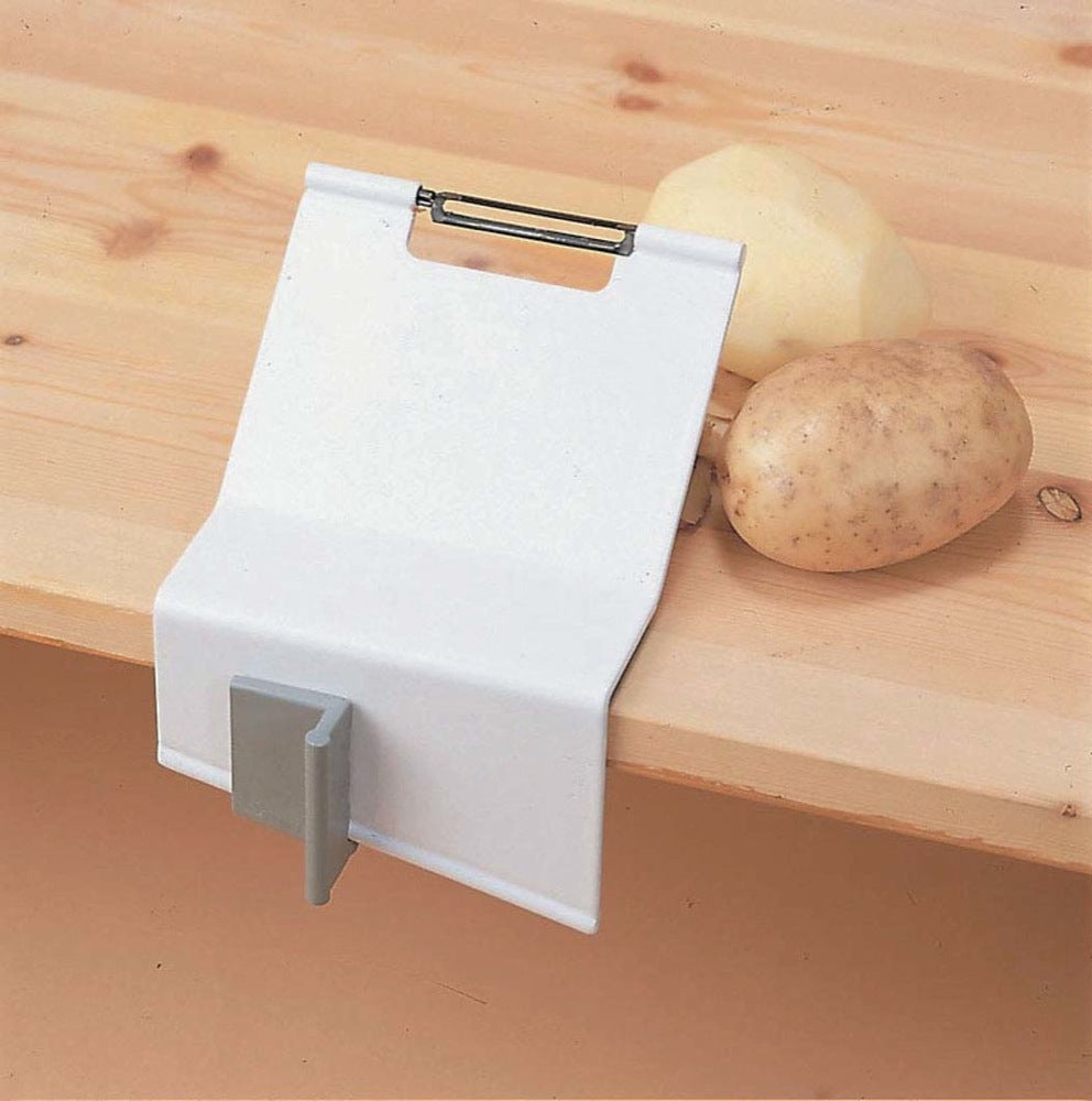 shows the homecraft gordon peeler and clamp fixed to a wooden surface with one peeled and one unpeeled potato beside it