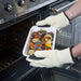 shows someone wearing the anti burn gloves to remove an oven dish of roasted vegetables from an oven
