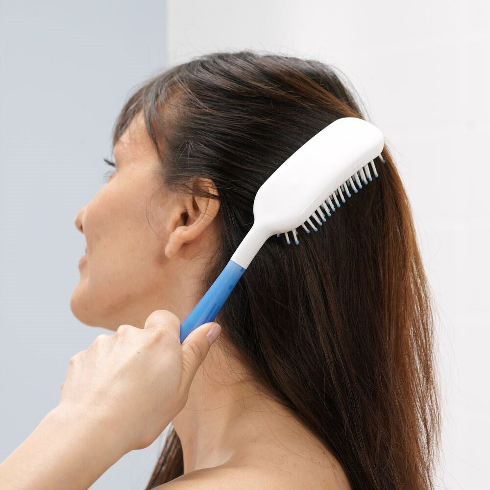 Woman using the Etac Long Handled Hair Brush