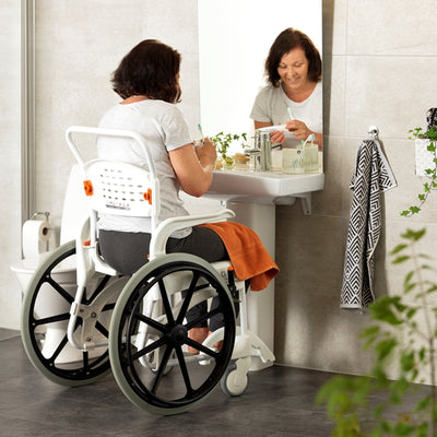 shows a woman using the Etac self propelled chair to get her to the bathroom sink to brush her teeth