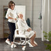 The image shows a user and carer with the Etac Clean Height Adjustable Shower Commode Chair