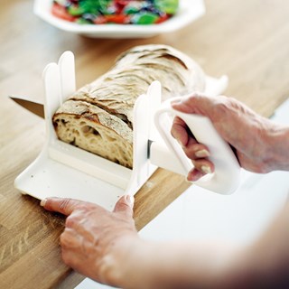 the image shows a loaf of bread being chopped on the Etac chopping board