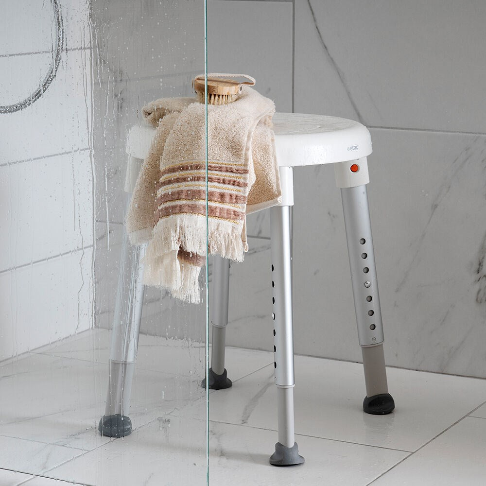 Easy shower stool in shower with a towel and brush on top of it
