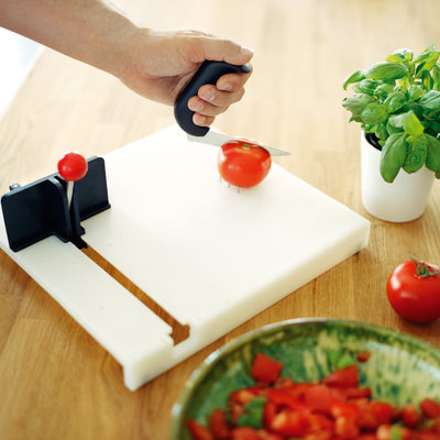 shows an Etac Fix Food Preparation System being used to chop a tomato