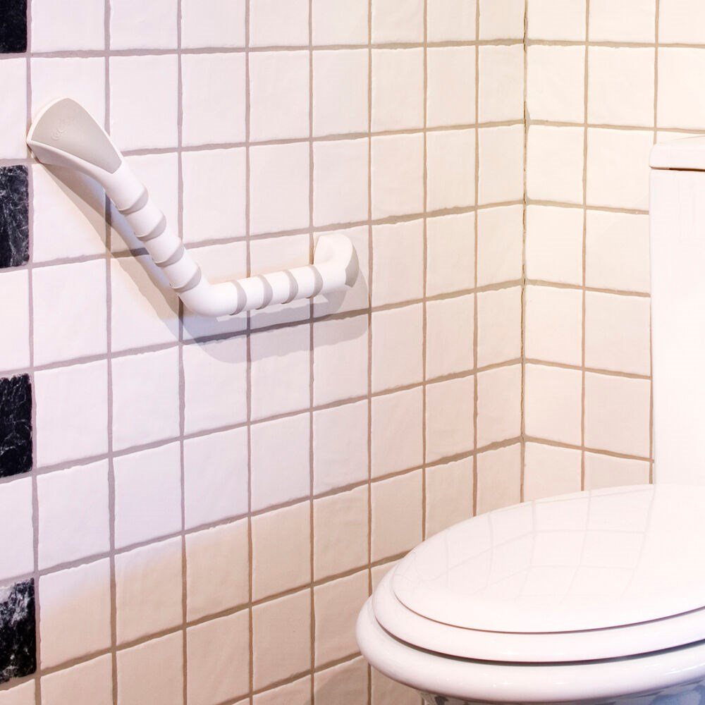 An angled Etac Grab Bar fixed onto a tiled wall in a bathroom next to a toilet