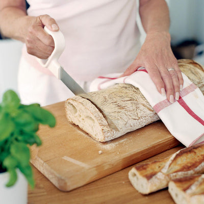 The Etac serrated kitchen knife cutting some bread